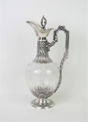 un pichet ancien en verre plaqué argent, muni d'une anse, sur fond blanc