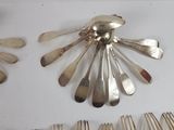 a lot of silver spoons and forks laid out on a table