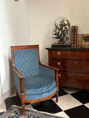 une chaise bleue dans un coin d'une pièce dont le sol est à carreaux noirs et blancs