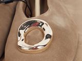 pair of tan sued shoes with a gold ring on top of them