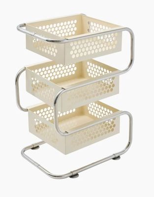 un panier de rangement blanc à trois niveaux posé sur un support en métal