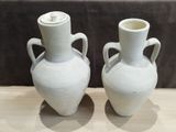 two white vases that are sitting on a table
