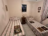 two beds in a room with a chandelier and a picture on the wall