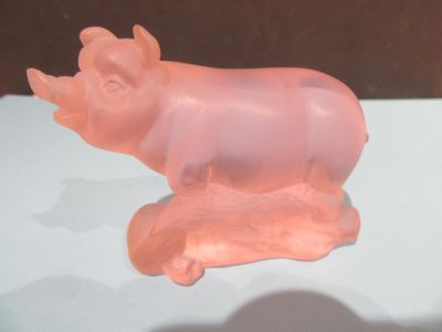 une figurine de cochon rose posée sur une table blanche