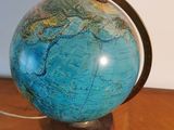 a blue globe on a wooden table with a white wall in the background