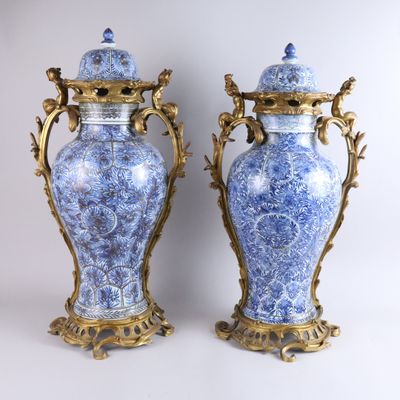 paire de vases bleus et blancs avec des anses et des couvercles dorés