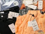 a pile of clothes and a pair of sunglasses on a bed