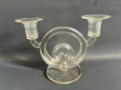 un bougeoir en verre transparent sur lequel sont posées deux bougies