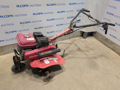 a red lawn mower sitting on top of a cement floor next to a wall