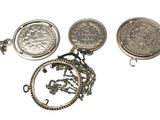 plusieurs types de bijoux en argent, dont une pièce de monnaie et un collier