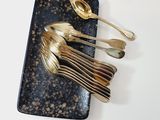a black plate with gold spoons and silver spoons on it