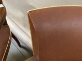 several brown leather chairs are lined up against a white wall