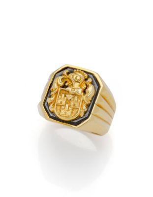 a close up of a gold ring with a coat of arms on it