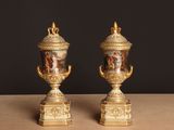 une paire de vases anciens posés sur une table, sur fond noir