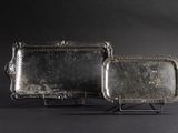 pair of silver trays on stand against a black background