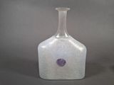 a glass bottle with a purple dot on it
