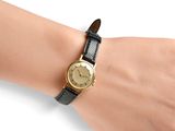 someone is wearing a gold watch on their wrist on a white surface