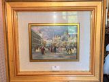 framed painting of a street scene with people and buildings in the background