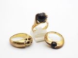 three gold rings with black stones on them on a white surface