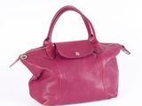 the pink leather handbag is sitting on a white surface