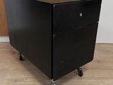a black filing cabinet with wheels on a wooden floor
