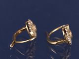 pair of gold and diamond earrings on a blue surface