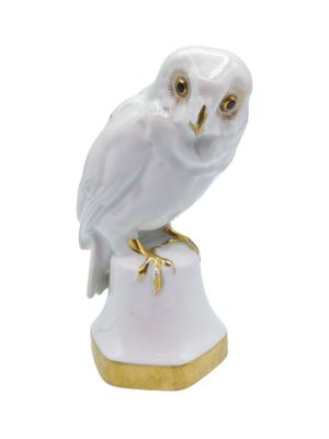 an owl figurine sitting on top of a white pedestal