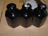 trois bouteilles noires vides posées sur une boîte en carton
