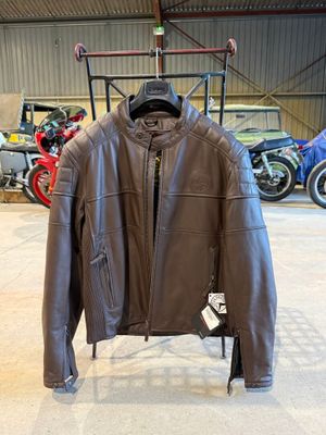 une veste en cuir suspendue à un porte-vêtements dans un garage, avec des motos en arrière-plan