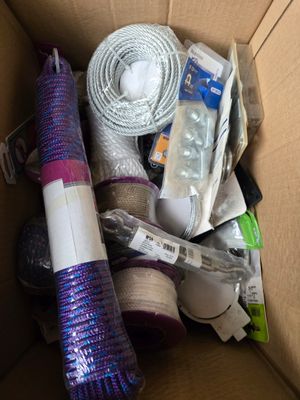 une boîte en carton contenant divers objets, notamment un rouleau de fil et un rouleau de ruban adhésif