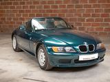 a green bmw sports car parked in front of a brick wall