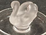 a glass swan sitting on a glass plate on a table