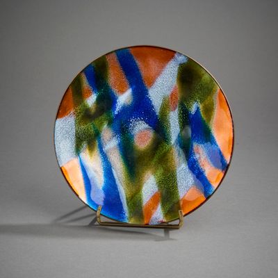 a colorful plate on a metal stand on a gray surface