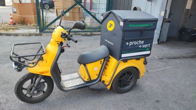 a yellow scooter with a box on the back of it
