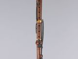 a wooden clarinet on a clear stand with a grey background
