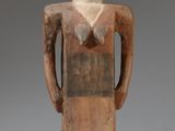 an image of a wooden statue of a man with his hands in his pockets