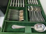 a green tray with silverware in it on a table