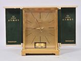 a gold clock with a green cover on it