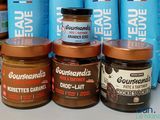 several jars of peanut butter sit on a table in front of blue bags