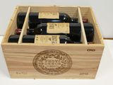 four bottles of wine in a wooden box on a table