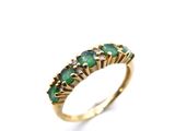 a close up of a gold ring with green stones