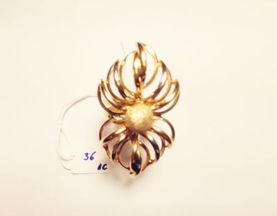 a close up of a gold spider brooch on a white surface