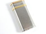 un briquet argenté et doré posé sur une surface blanche