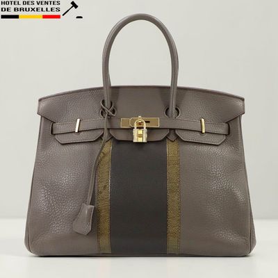 un sac à main marron et noir posé sur une table blanche