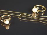 deux bagues et un collier posés sur une surface noire