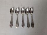 six spoons are lined up in a row on a white surface