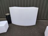 two white stools and a white table in front of a building