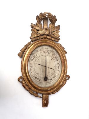 a gold clock on a white wall with a bird on it