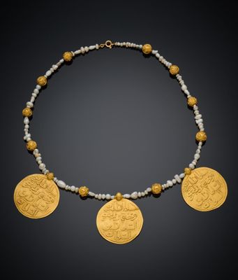un collier composé de pièces d'or et de perles sur fond noir