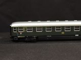 a green and white train car sitting on a black surface